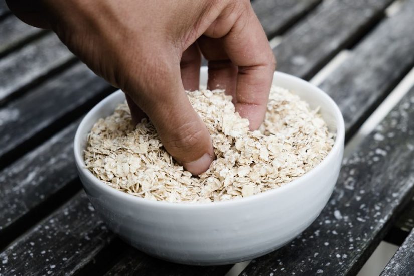 man-grabbing-some-rolled-oats-from-a-bowl-royalty-free-image-1046092530-1554813256
